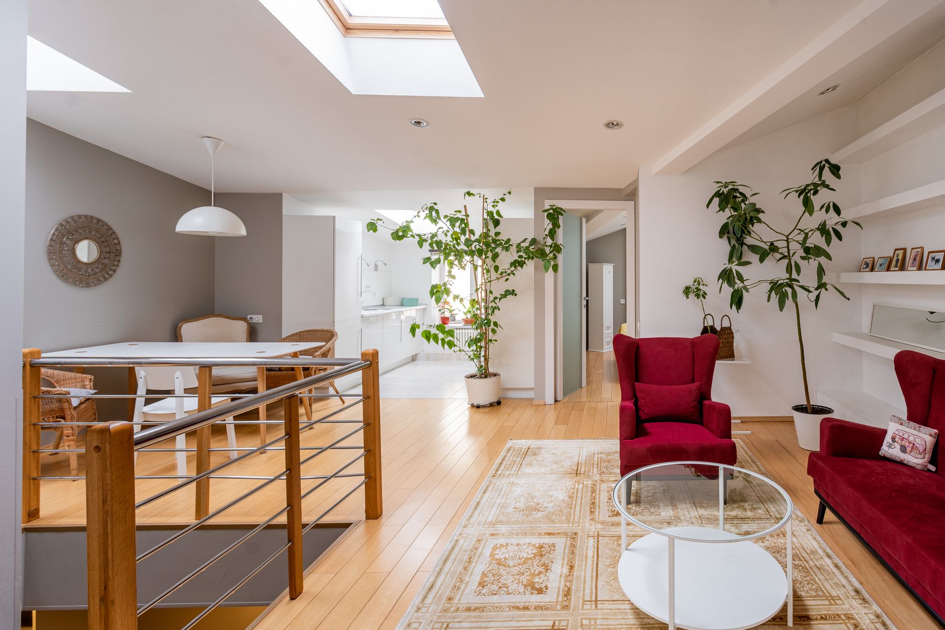 A bright, contemporary living room featuring red armchairs and minimalist design elements.