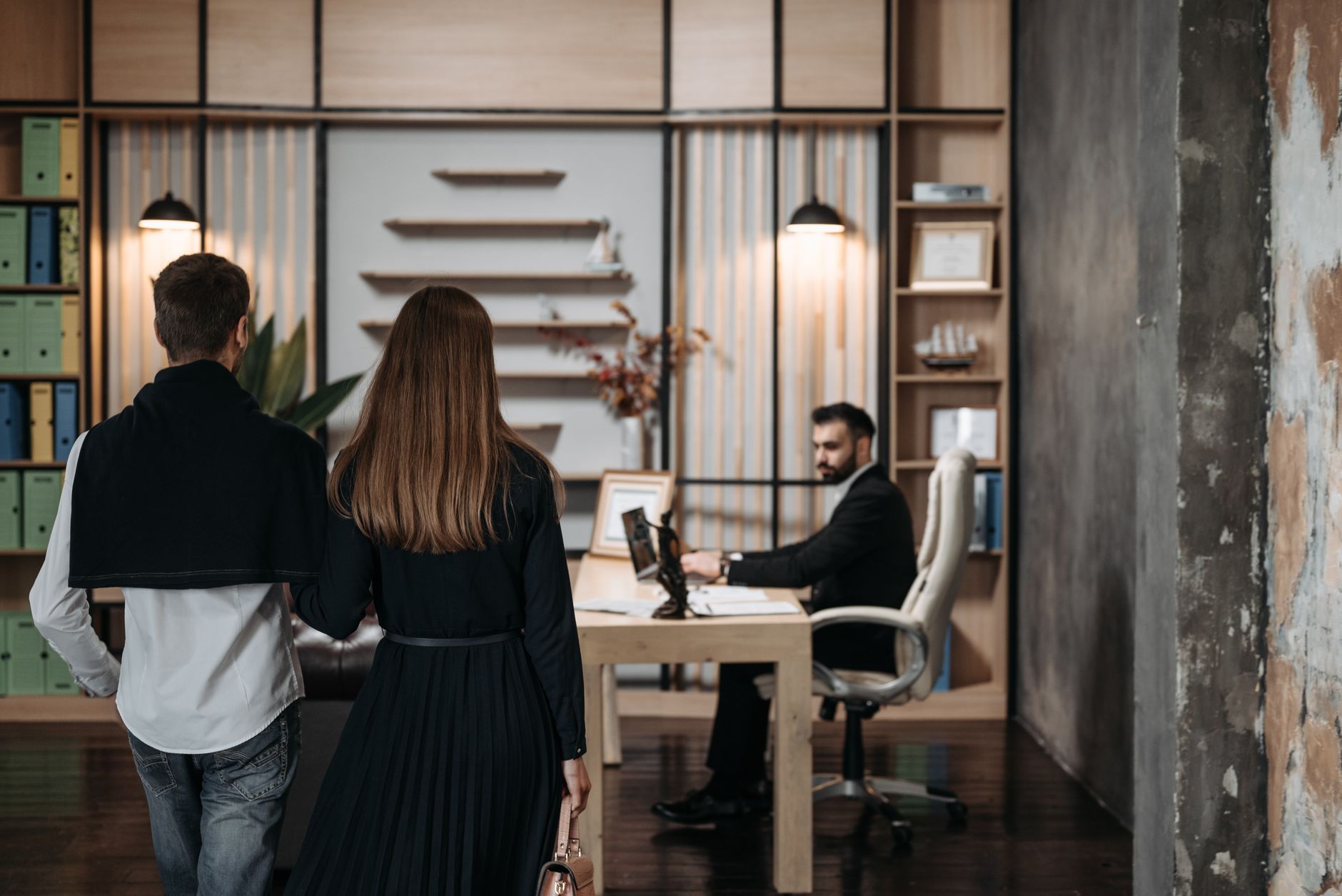 A couple approaches a lawyer in a contemporary office setting for a professional consultation.