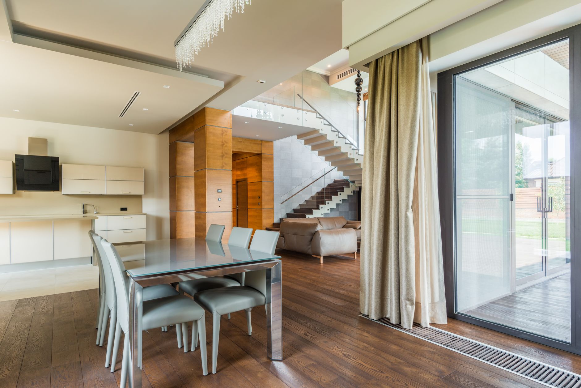 Spacious open-plan dining and living area featuring minimalist design and large glass wall.